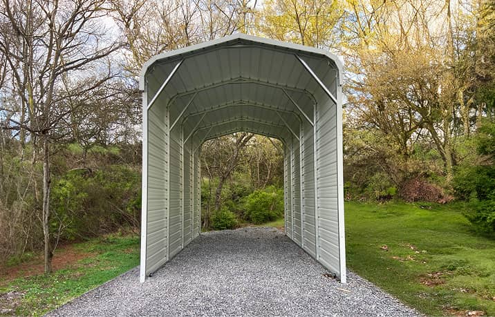 Tan regular style roofmetal carport sheltering dark sedan on concrete driveway