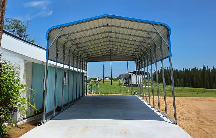 Regular style roof metal carport with red SUV parked underneath on gravel surface