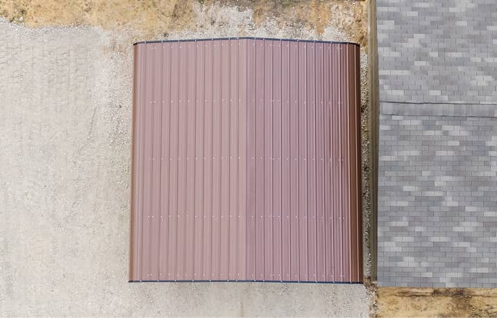 Beige and white regular style roof metal carport housing black pickup truck