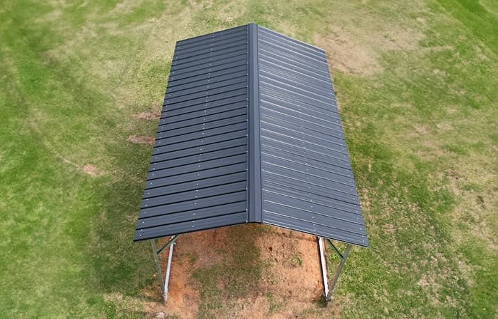 Vertical style roof metal carport sheltering white RV in snowy winter