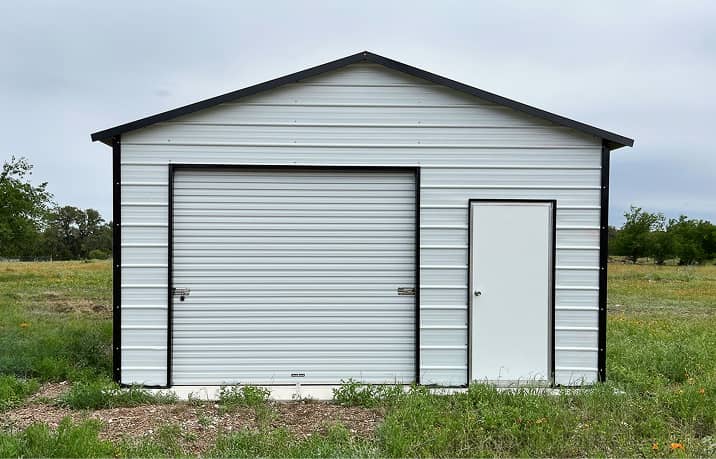 Beige boxed-eave style roof metal garage with two roll-up doors and walk-in door