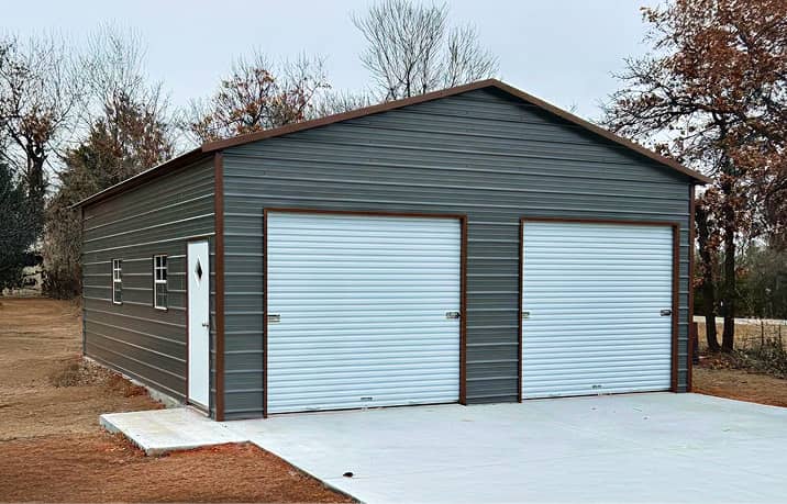 Blue boxed-eave style roof metal garage with single roll-up door on gravel surface
