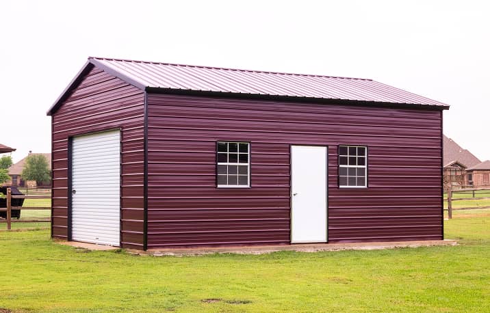 Vertical style roof metal garage building with three roll-up doors and one walk-in door