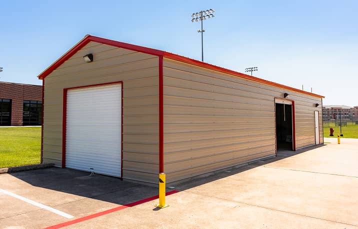 Brown vertical style roof metal garage with two overhead doors and walk-in door