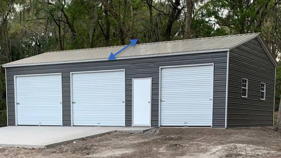 A gray two-car garage with a vertical-style roof and white doors and trim