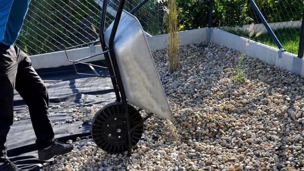 worker with a wheelbarrow pouring gravel into foundation