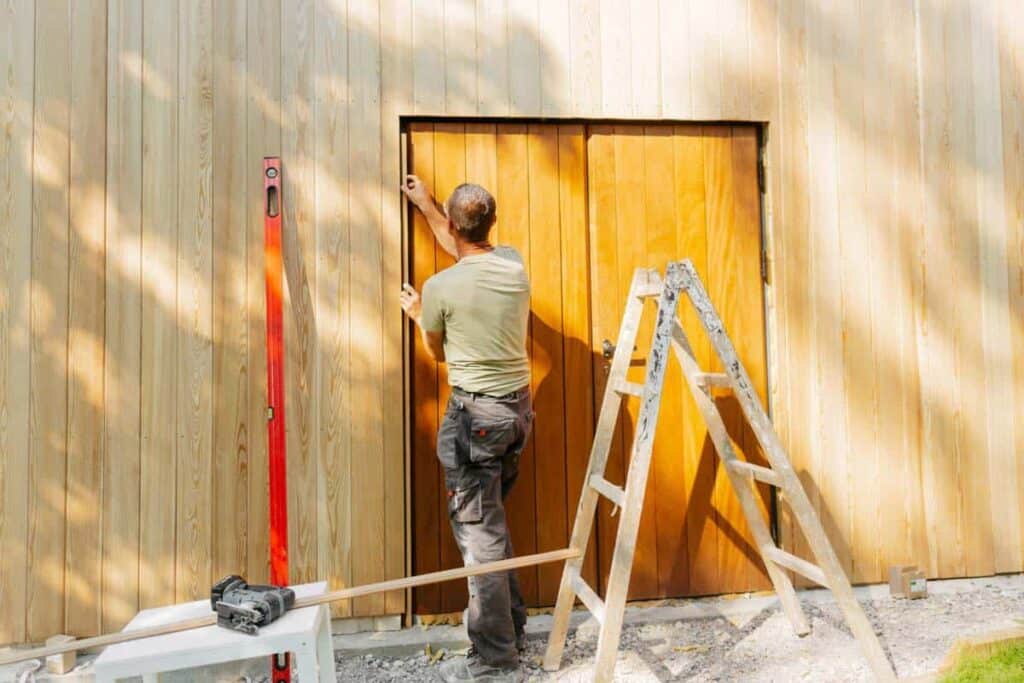 man sealing up cracks of a shed door