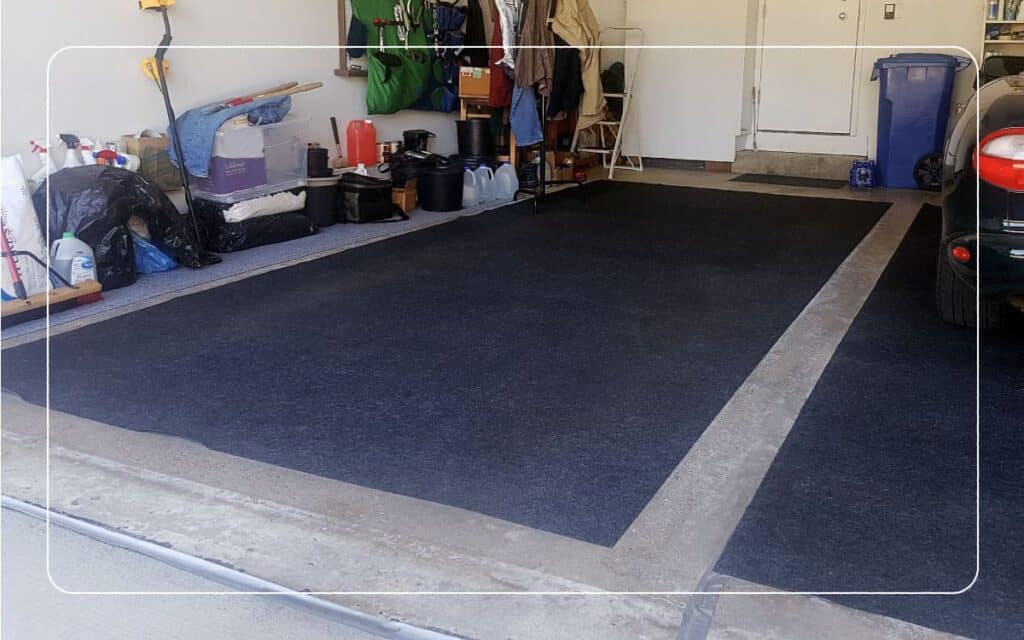 Two navy blue oil absorbing mats sit on the floor of a garage.