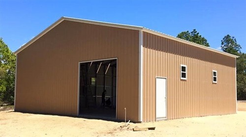A tan metal building with one garage door and one walk-in door