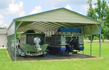 Two boats are covered by a partially-enclosed metal carport