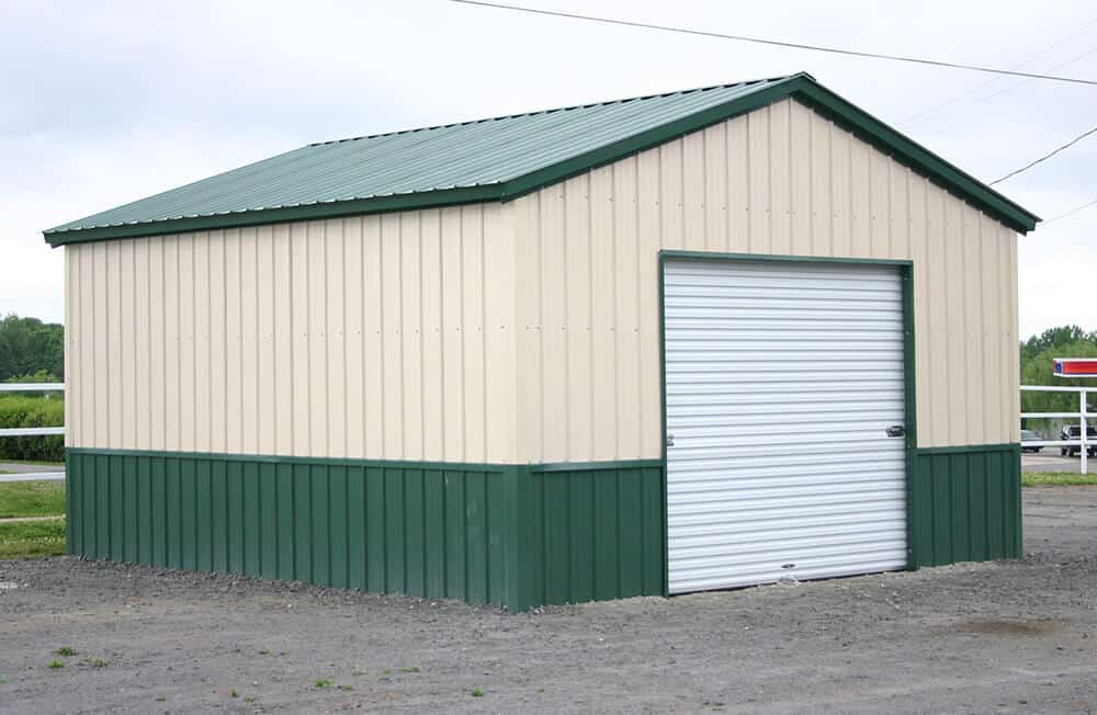 A two-tone steel building for sale in beige and green with a white garage door