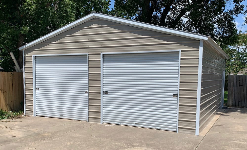 A tan two-car metal garage with two white garage doors