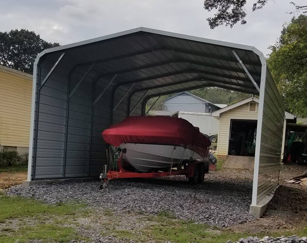A small boat on a trailer is sheltered under a sturdy metal boat carport