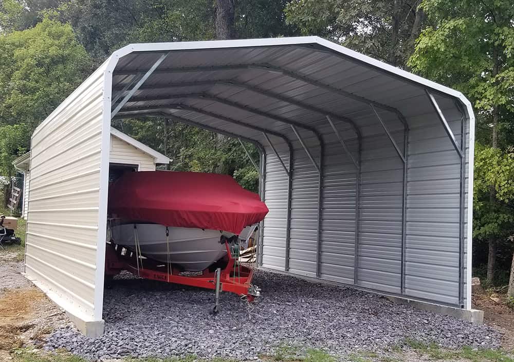 A boat protected under a partially enclosed metal carport