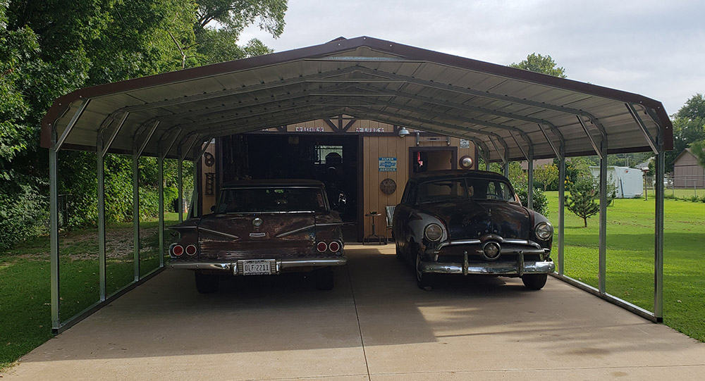 antique cars under a metal carport