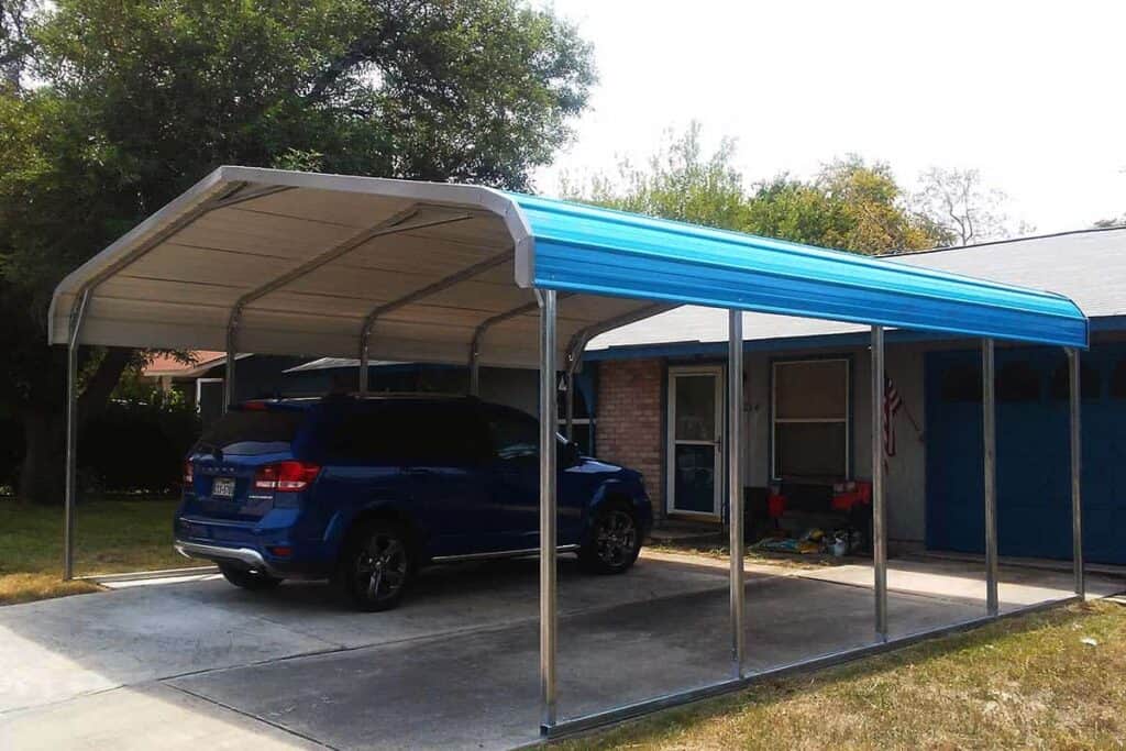 car parked beneath a blue carport in front of a house 