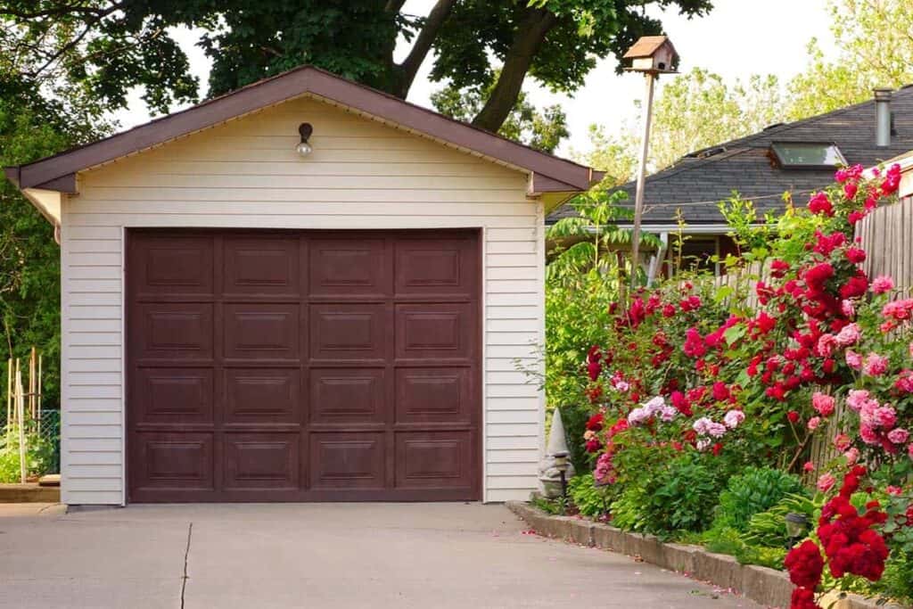 detached one-car garage next to flowers