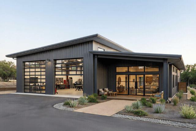 Modern dark metal garage building with glass garage doors and a covered entry patio.