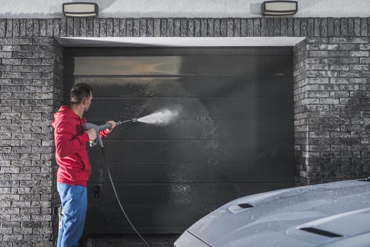 Man power washing a garage door