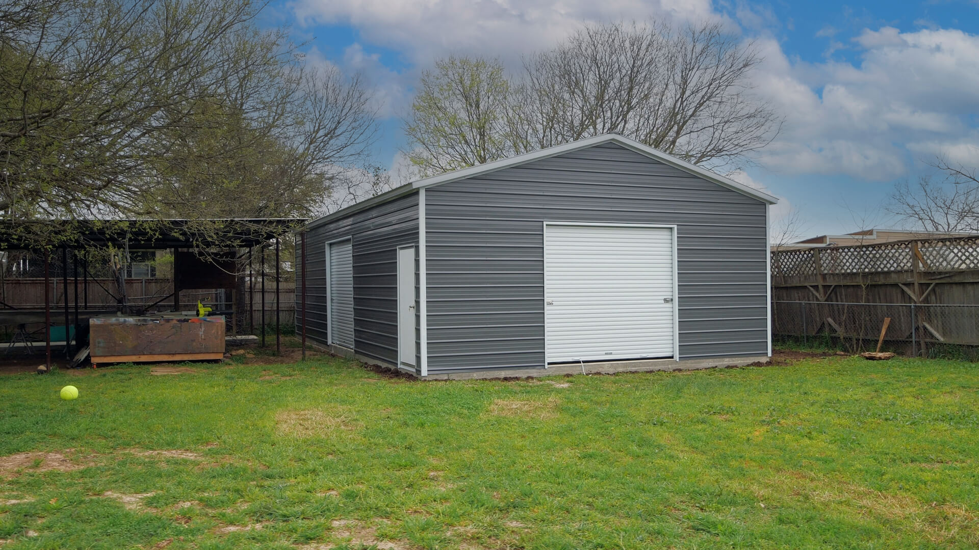 Gray 24-by-40-foot metal garage with front and side roll-up doors, a walk-in door, and white trim.