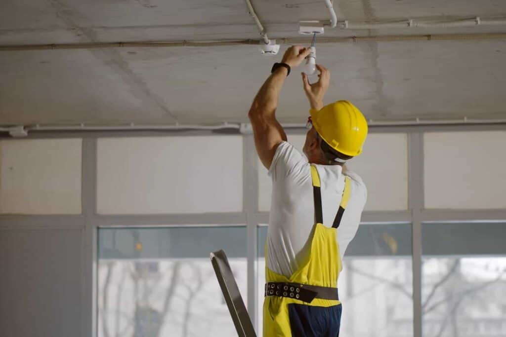 construction worker installing lights in a warehouse