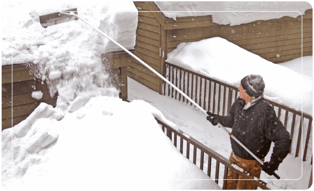 man clearing snow off a roof 