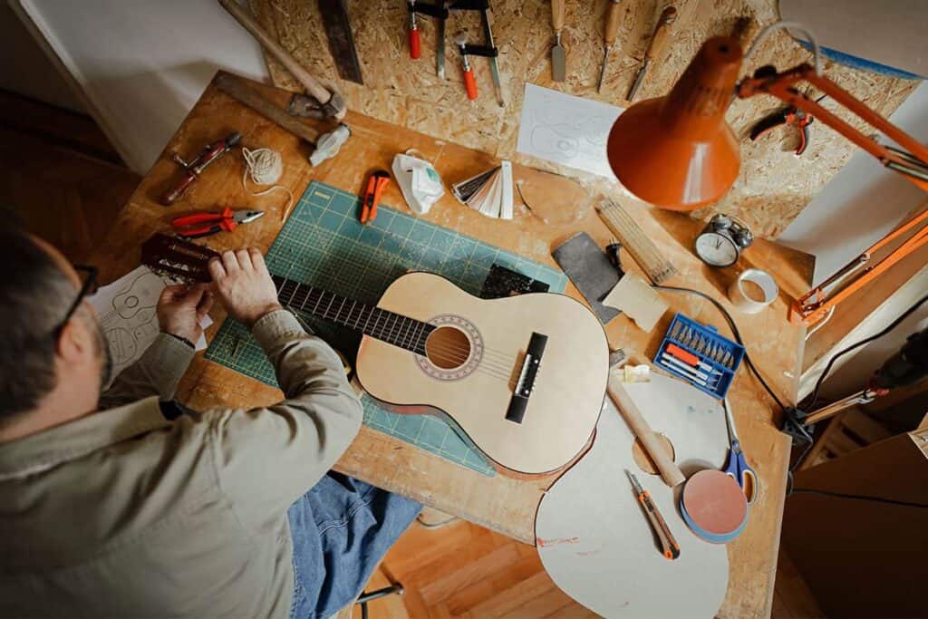 man working on guitar in converted shed studio