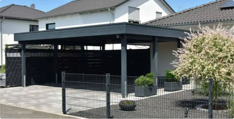 Modern flat-roof carport with dark wood paneling, attached to a white house