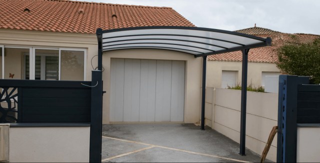 Modern arched carport with a translucent roof, installed in front of a garage.