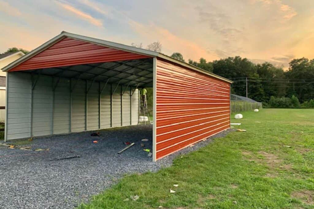 red carport on gravel foundation in a yard