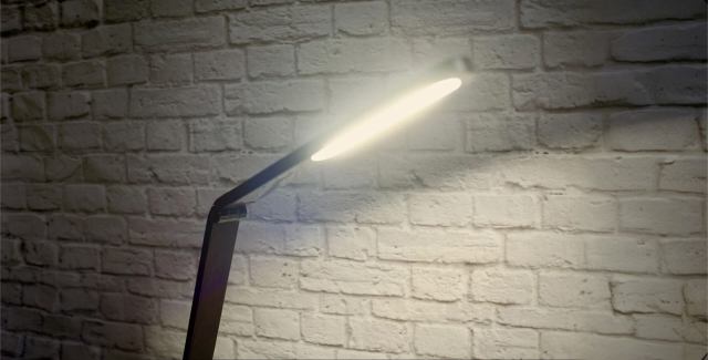 Modern desk lamp providing focused task lighting against a brick wall