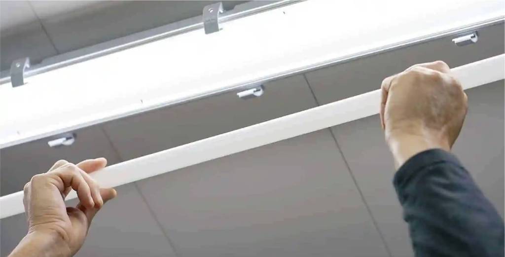 Hands replacing a fluorescent tube light