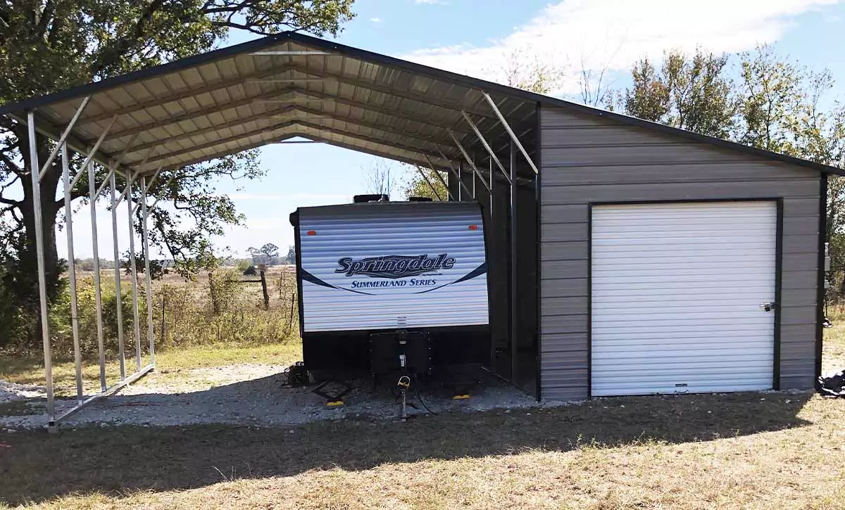 A carport covers an RV and features a connected storage area with four walls and a locked door. 