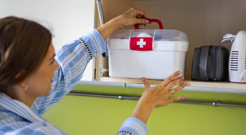 woman storing first aid kit in a cabinet