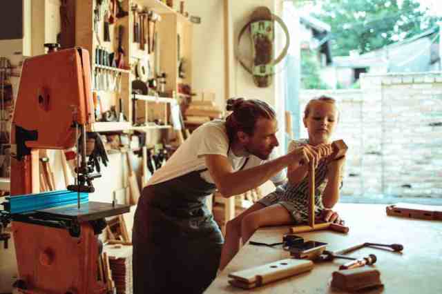 man with daughter woodworking in garage