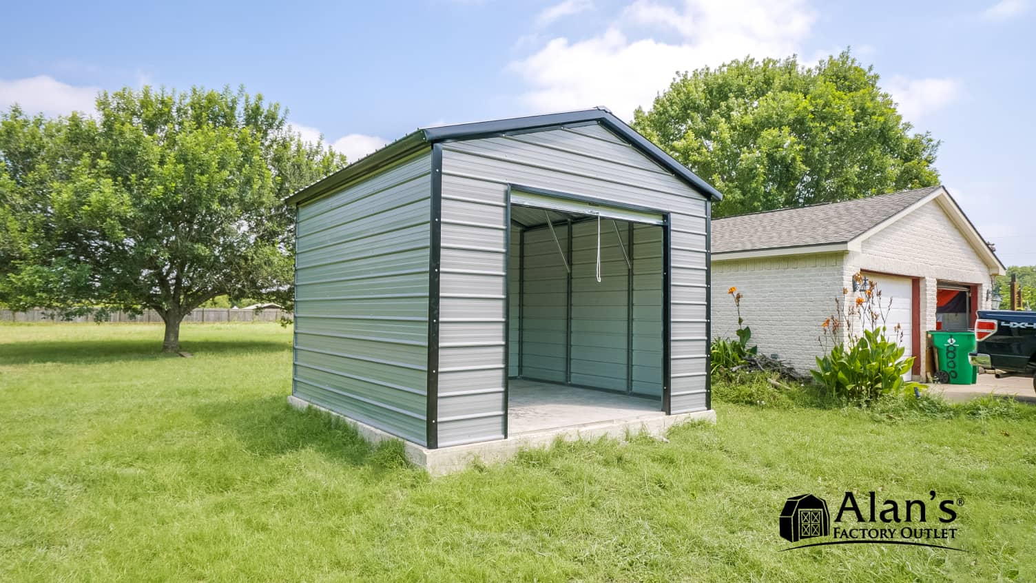 Gray metal garage building with open doors on residential lawn next to brick house