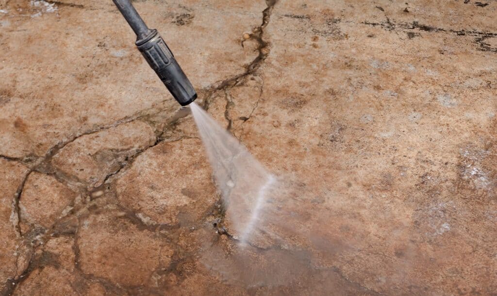 someone power washing a cracked concrete floor