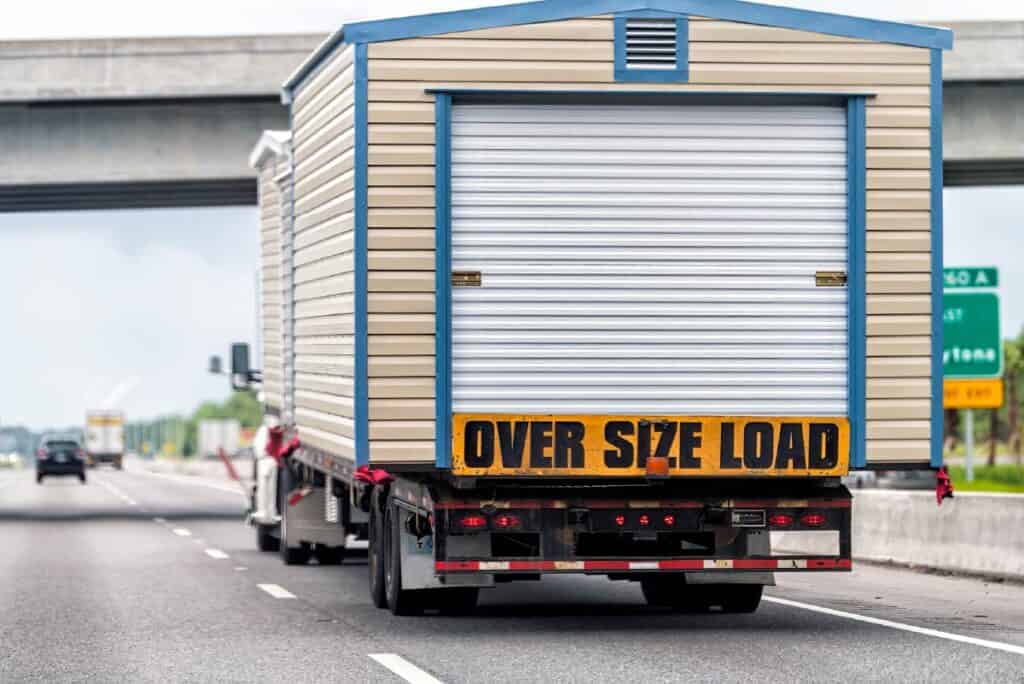 Truck moving large sheds on a flatbed trailer