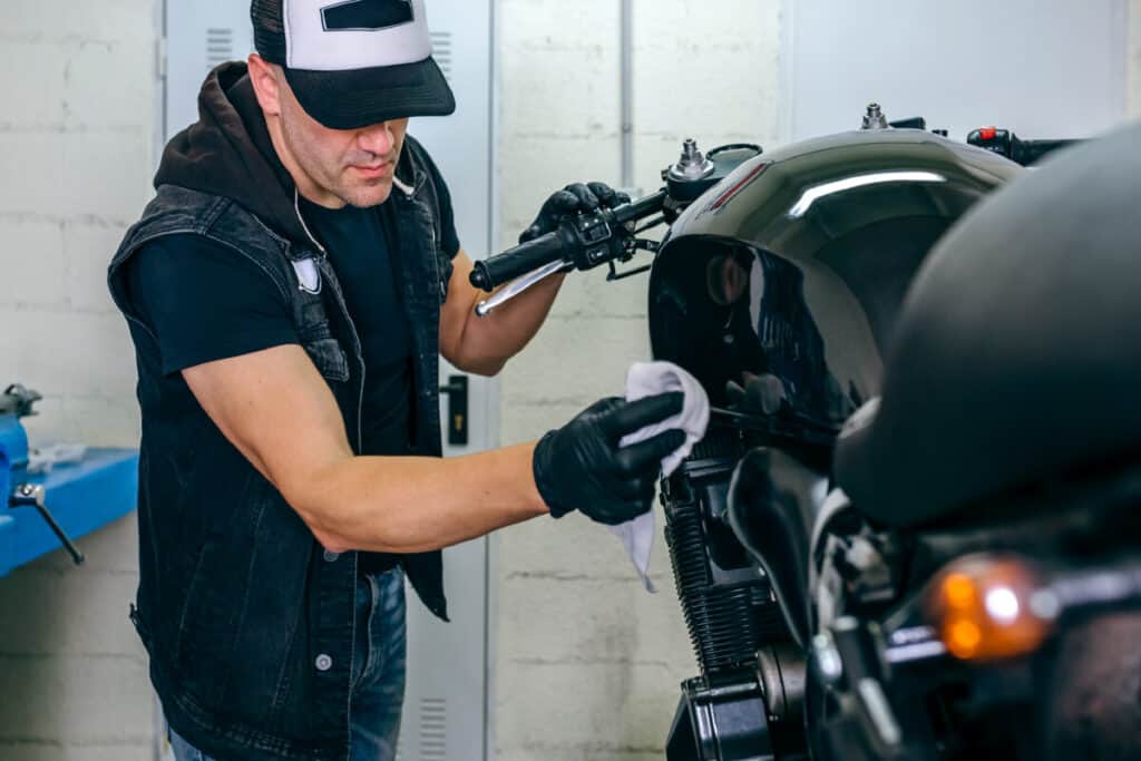 A man cleaning his motorcycle in a garage