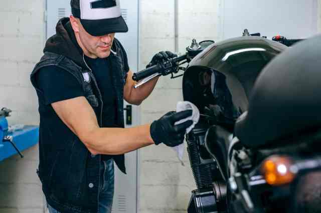 man cleaning motorcycle in storage building