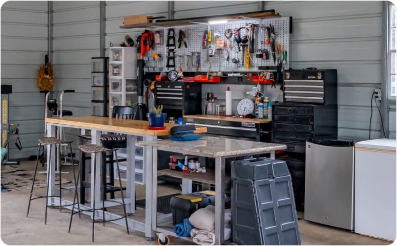 A workshop area in a garage with a workbench, storage containers, and hanging tools