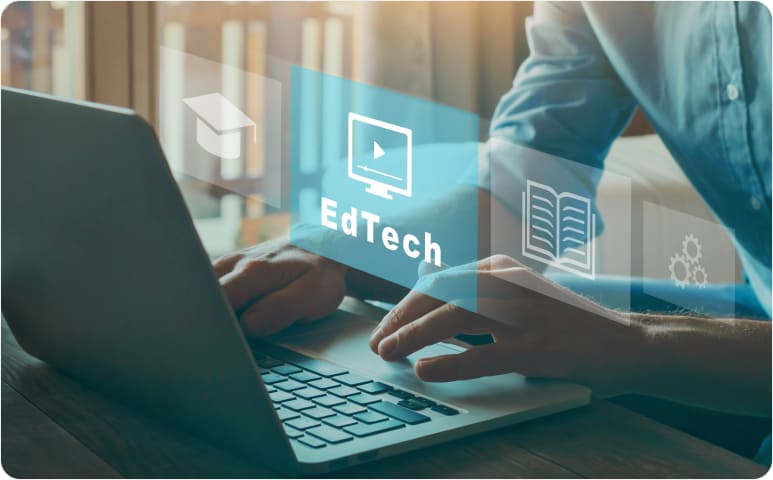A person at a laptop with a reflection of the word EdTech.