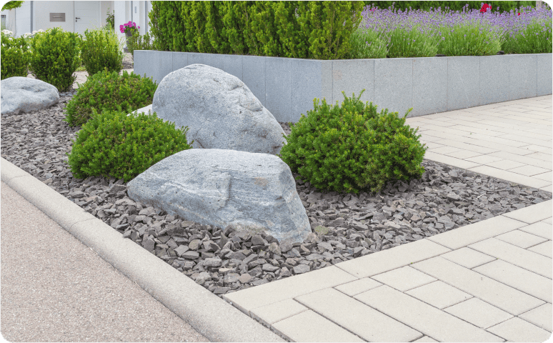Modern-style landscaping including a rock bed with large rocks, small stones, and shrubs, surrounded by brick pavers.