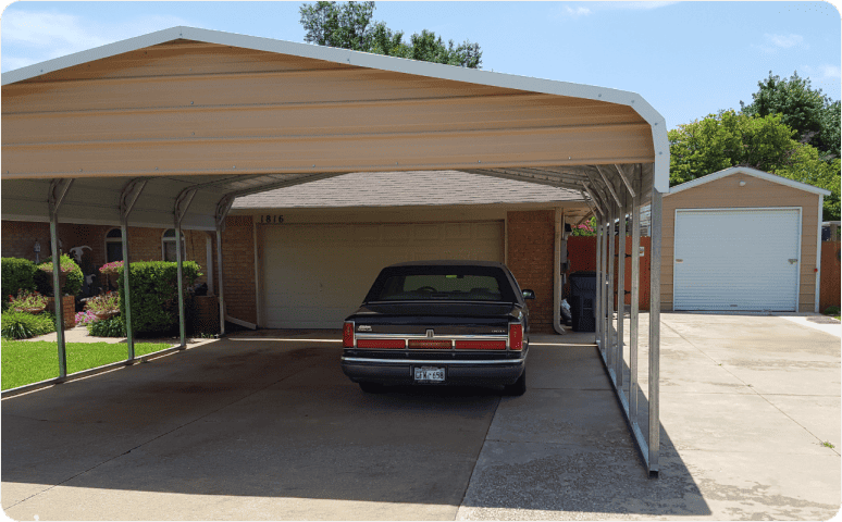 A metal carport sheltering a parked car in front of a home.