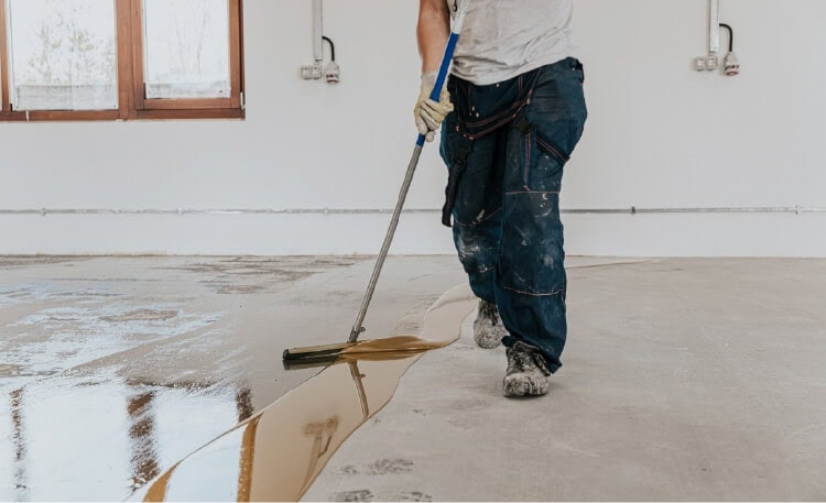 person adding epoxy coating to floor