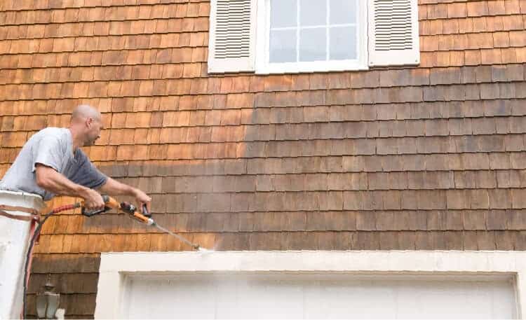 man power washing garage exterior