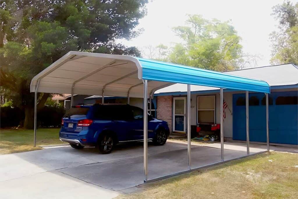 Blue car under a blue detached carport in front of a house.