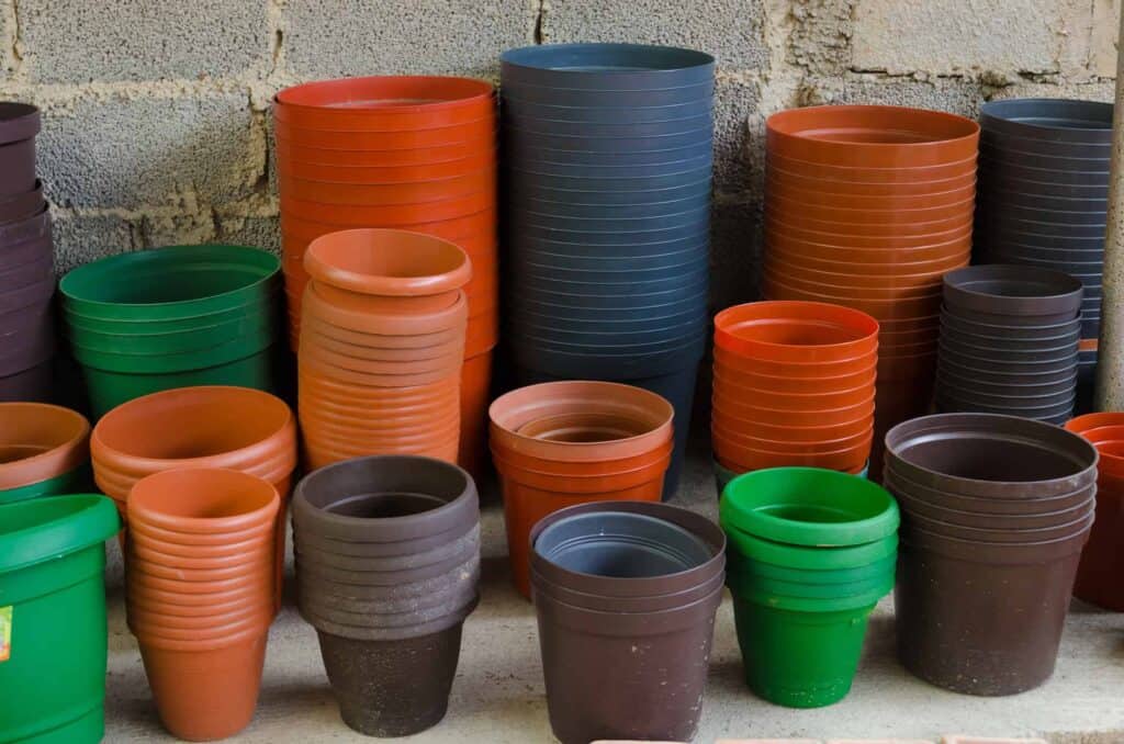 Stacks of variously colored plastic flowerpots neatly arranged in a garage.