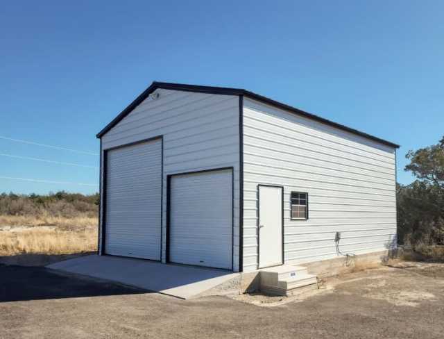 A large white garage with two garage doors, a walk in door and a window.