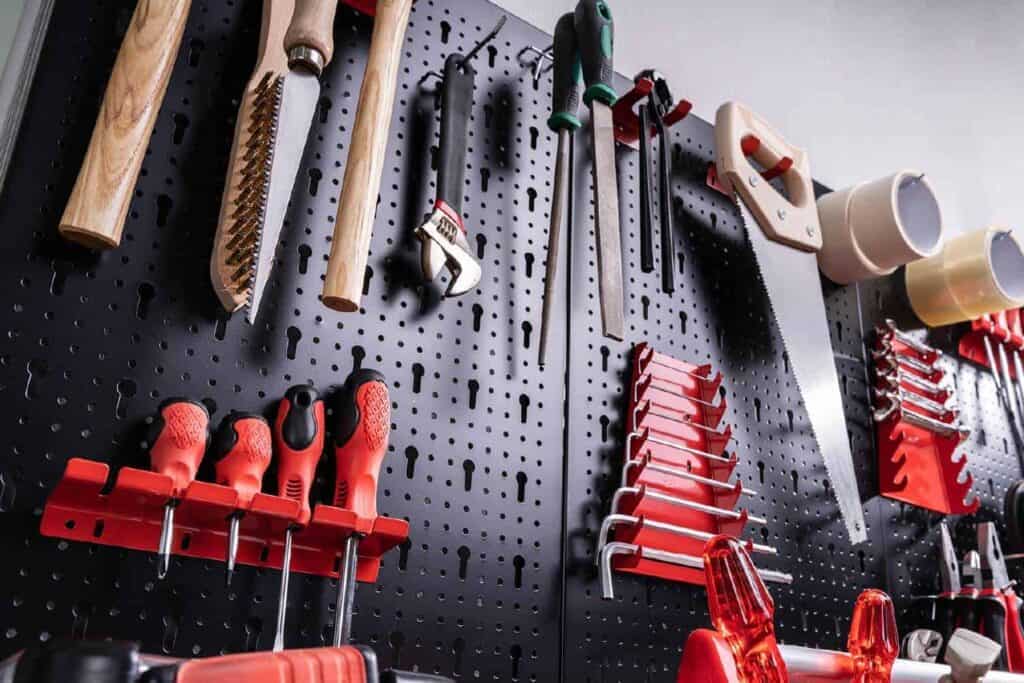 black pegboard mounted on a wall with red tools.